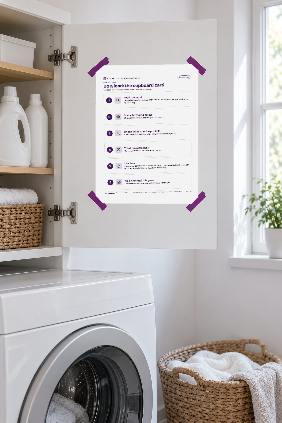 A sheet taped inside a white cabinet door above a washer with purple tape.
